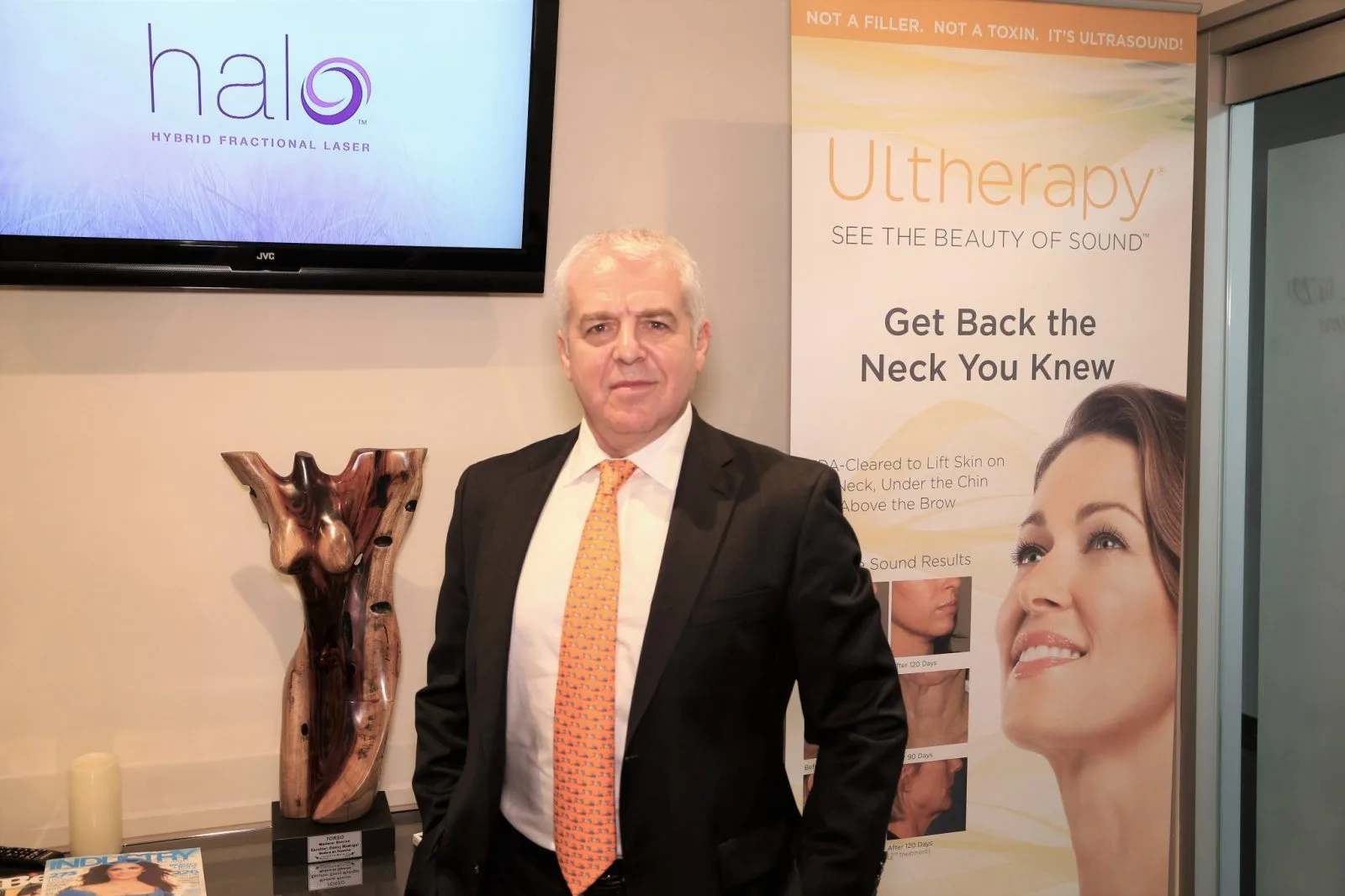 Dr. Boris Mordkovich standing in consultation room with Ultherapy and Halo laser displays